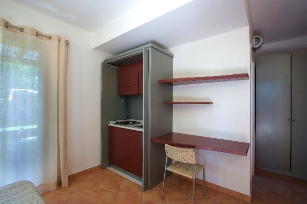 Un angolo cottura compatto con scaffali rossi, una sedia e un tavolo contro il muro.