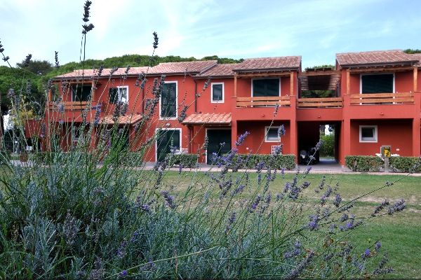Edificio rosso a due piani con tetto in tegole, circondato da vegetazione e lavanda in primo piano.