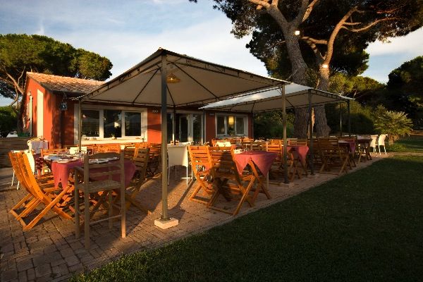 Terrazza esterna di un ristorante con tavoli apparecchiati e sedie in legno.