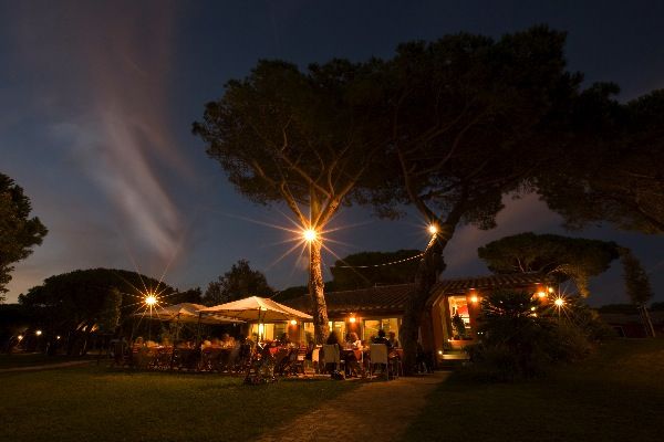 Ristorante all'aperto illuminato di sera, atmosfera calda.