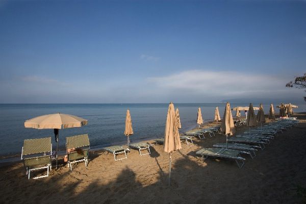 Lettini e ombrelloni chiusi su una spiaggia, vista mare sereno.