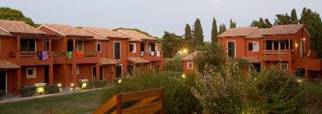 Complesso residenziale con case a due piani rosse, immerso nel verde.