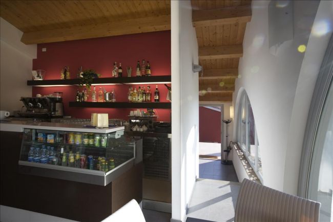 Interno di un bar con scaffali di bottiglie, frigorifero di bevande e arredi moderni.