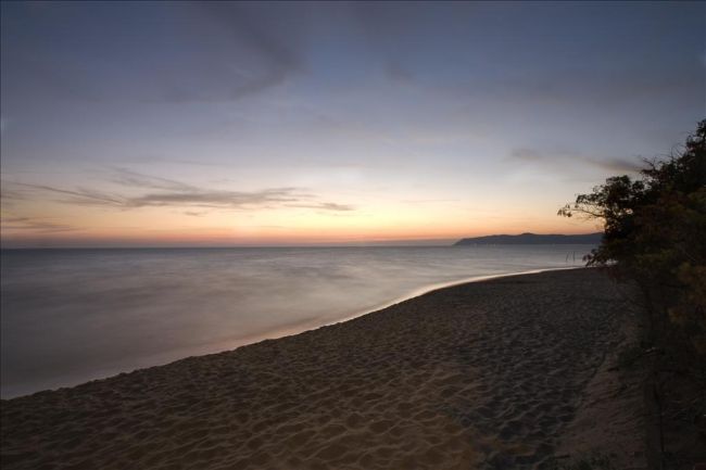 Spiaggia deserta al tramonto con cielo colorato e mare calmo.