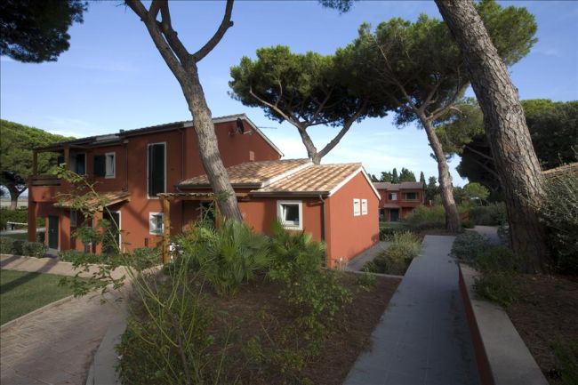 Edifici rossi immersi tra alberi alti, con vialetti pavimentati.