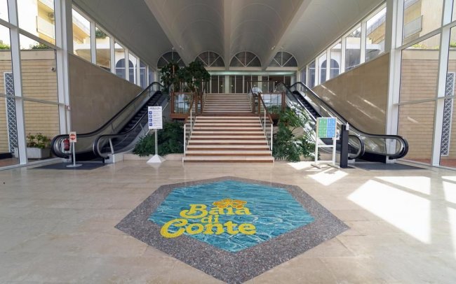 Ingresso con scale e due scale mobili. Logo 