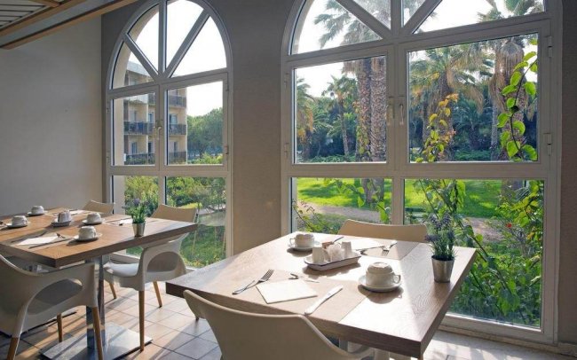 Sala da pranzo con finestre ampie che mostrano il giardino.