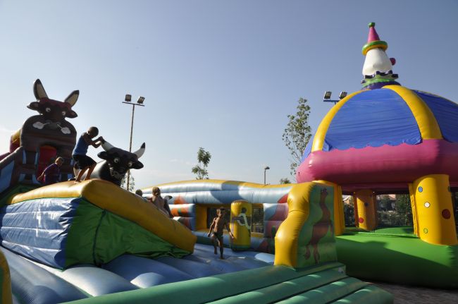 Bambini giocano su un castello gonfiabile colorato all'aperto sotto un cielo limpido.