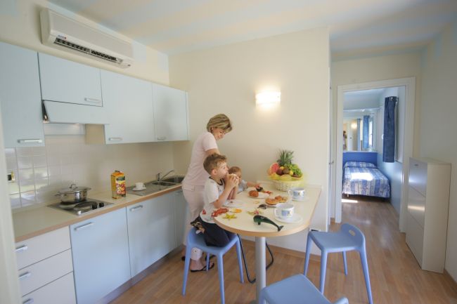 Interno moderno di una cucina con madre e due bambini che fanno colazione.