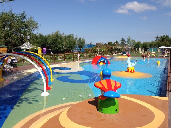 Piscina con giochi d'acqua colorati e area spray.