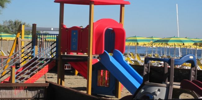 Un'area giochi sulla spiaggia con uno scivolo colorato.