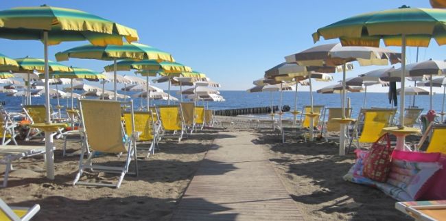 Spiaggia con ombrelloni gialli e verdi e lettini.