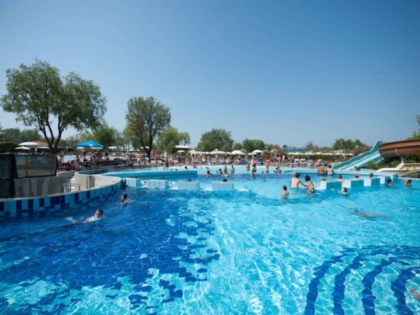 Piscina con scivolo e persone che nuotano.