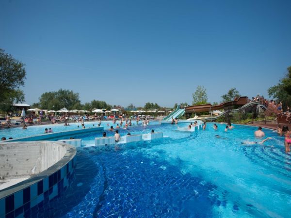 Piscina affollata con lettini e scivolo.
