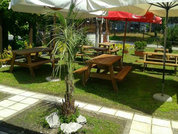 Tavoli da picnic in legno con ombrelloni su prato.