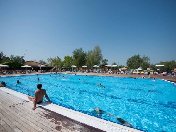 Piscina con bagnanti e ombrelloni bianchi.