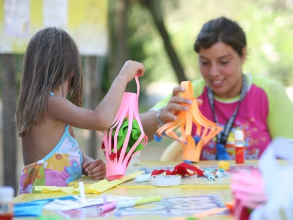 Bambina e donna fanno un lavoretto con carta colorata.