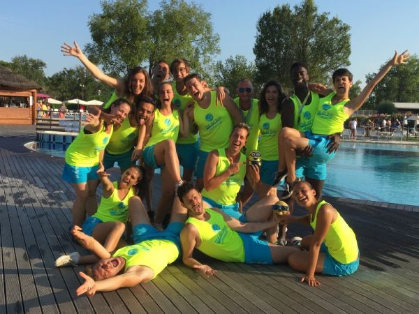 Gruppo di persone in canotte gialle posa allegra vicino a una piscina.
