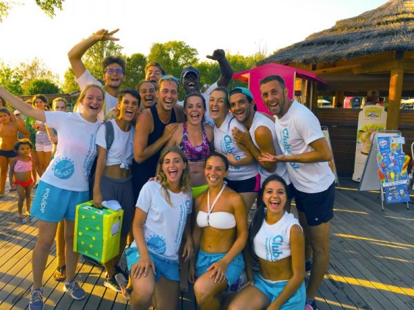 Gruppo di persone sorridenti su una terrazza soleggiata.