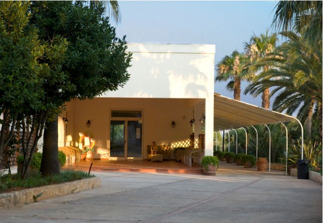 Edificio bianco con ingresso ombreggiato e piante.