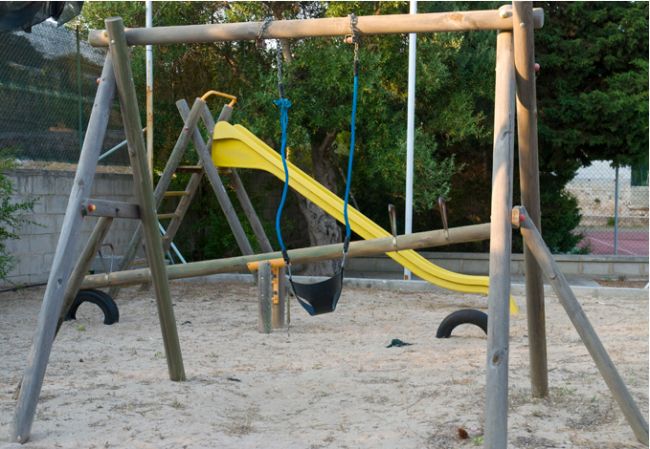 Un parco giochi con altalena e scivolo giallo.