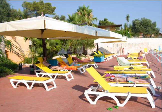 Lettini gialli sotto ombrelloni vicino alla piscina.