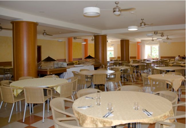 Sala da pranzo con tavoli rotondi apparecchiati.