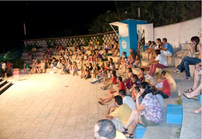 Anfiteatro esterno con spettatori seduti.