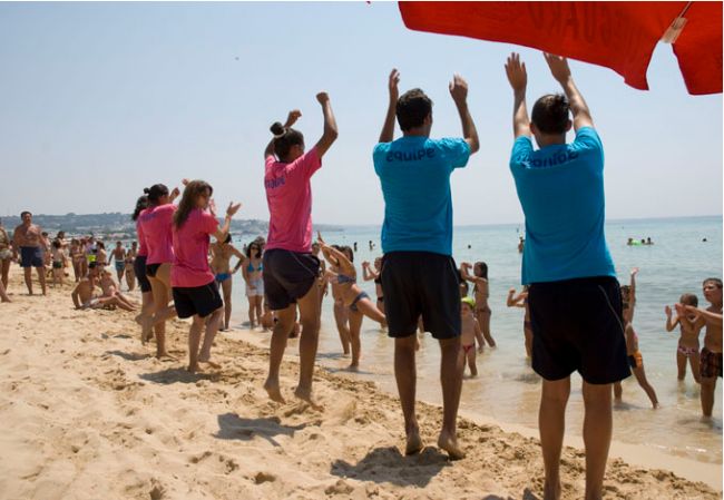 Persone che ballano sulla spiaggia in riva al mare.