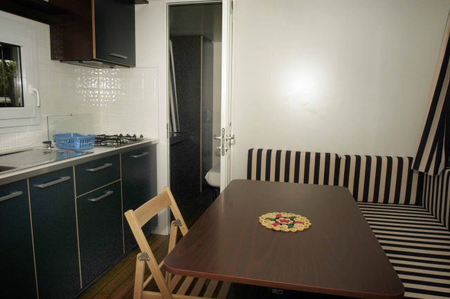 Cucina compatta con tavolo e sedute a righe.