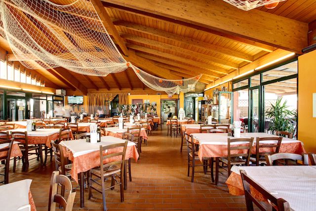 Ristorante con tavoli apparecchiati e soffitto in legno.