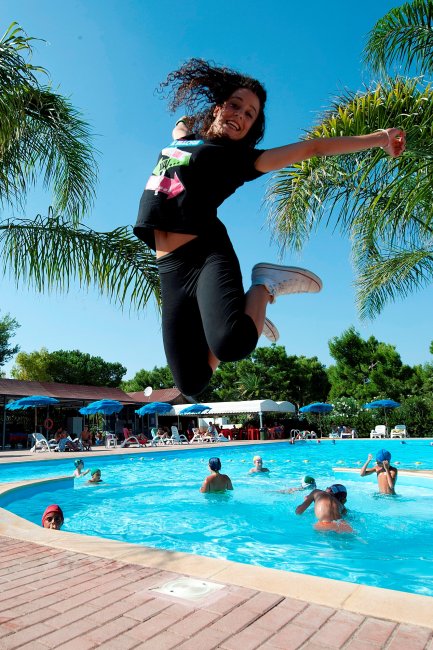 Persona salta felice vicino a una piscina.