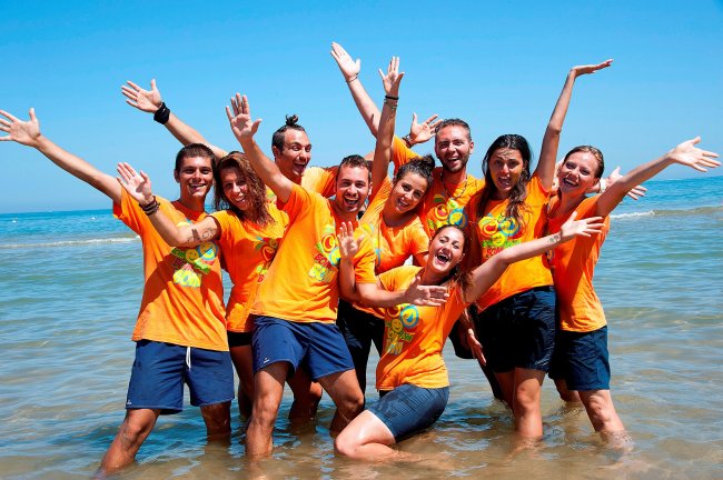 Gruppo allegro in magliette arancioni al mare.