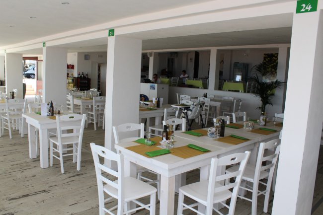 Ristorante interno con tavoli apparecchiati, tono bianco e verde.