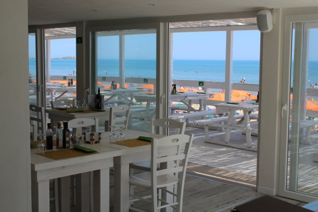 Ristorante con vista mare, tavoli bianchi.
