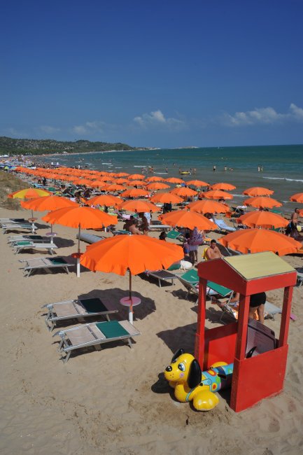 Spiaggia con ombrelloni arancioni e sdraio.