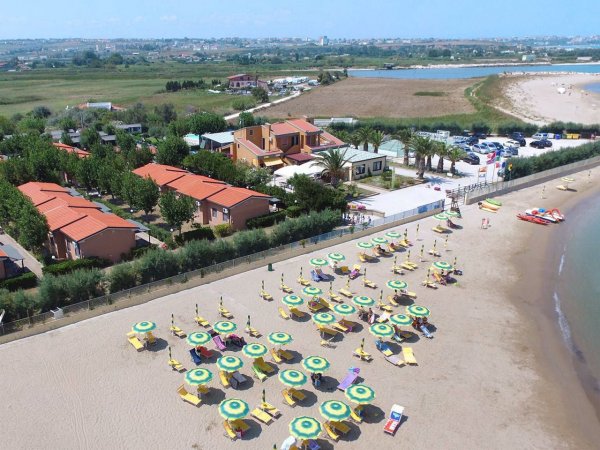 Spiaggia con ombrelloni e villette rosse in lontananza.