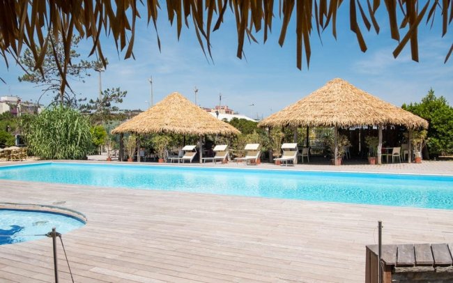 Piscina con tettoie di paglia e lettini.