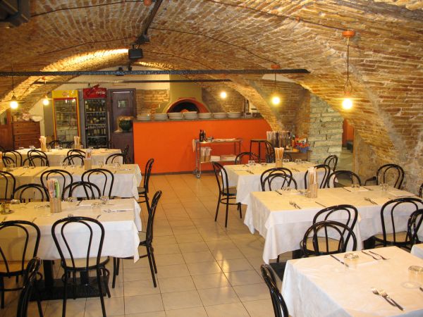 Ristorante con archi in mattoni e tavoli apparecchiati con tovaglie bianche.