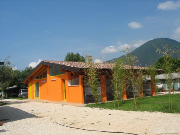 Edificio dipinto di arancione acceso con tetto a spiovente, circondato da vegetazione.