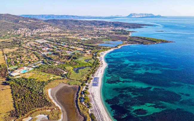 Spiaggia e mare cristallino con paesaggio costiero.