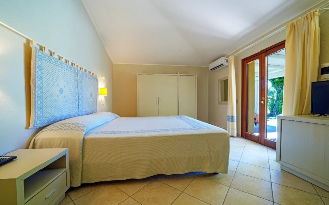 Camera da letto luminosa con letto matrimoniale e tende chiare.